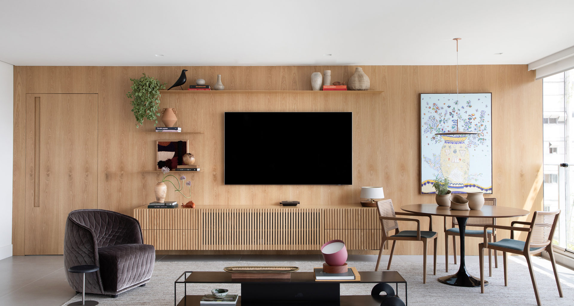 na foto sala com tv mesa com quatro cadeiras, mesa de centro e poltrona