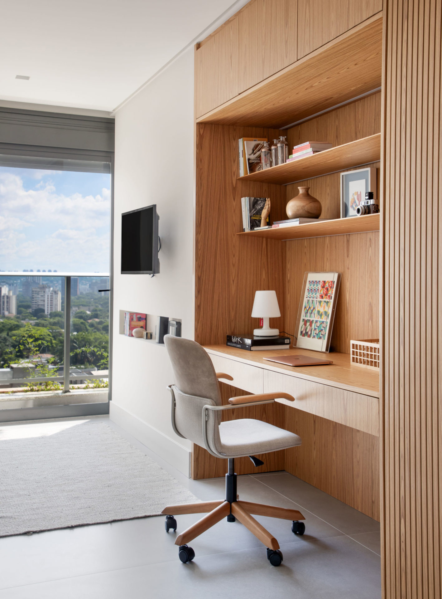 na foto um ambiente com mesa de trabalho e tv na parede