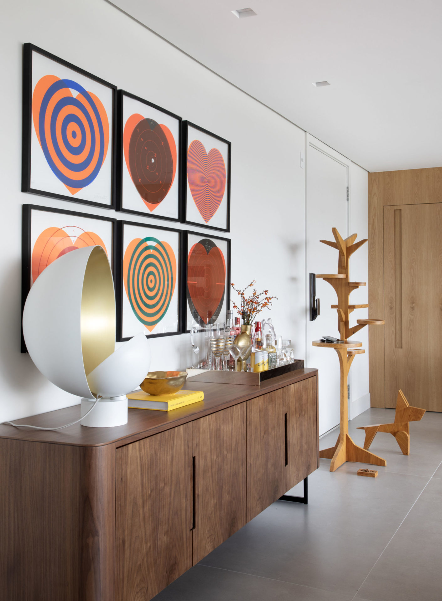 na foto bufe com objetivos decorativos, seis quadros na parede e piso de porcelanato