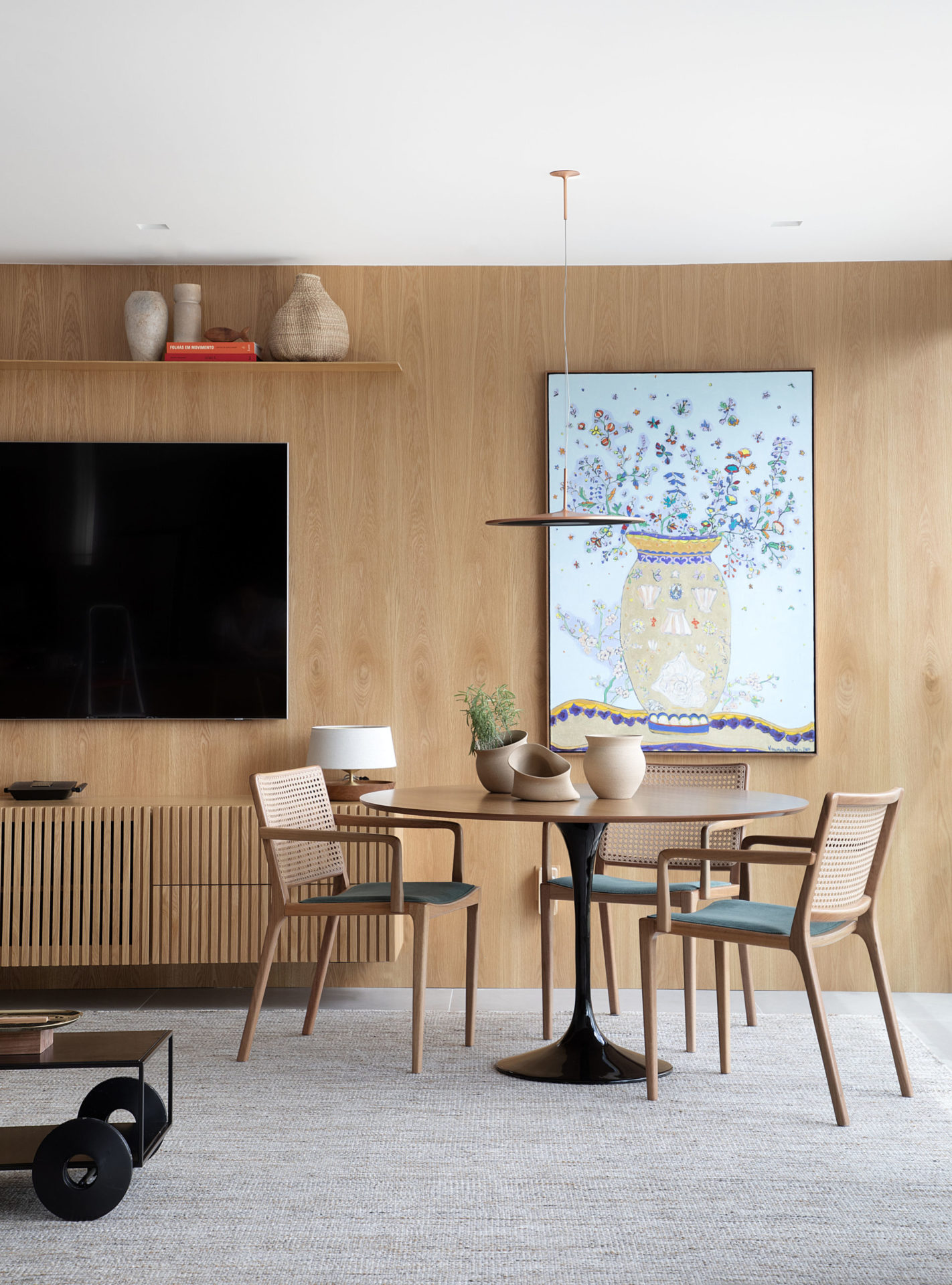 na foto sala com tv na parede e mesa com quatro cadeiras