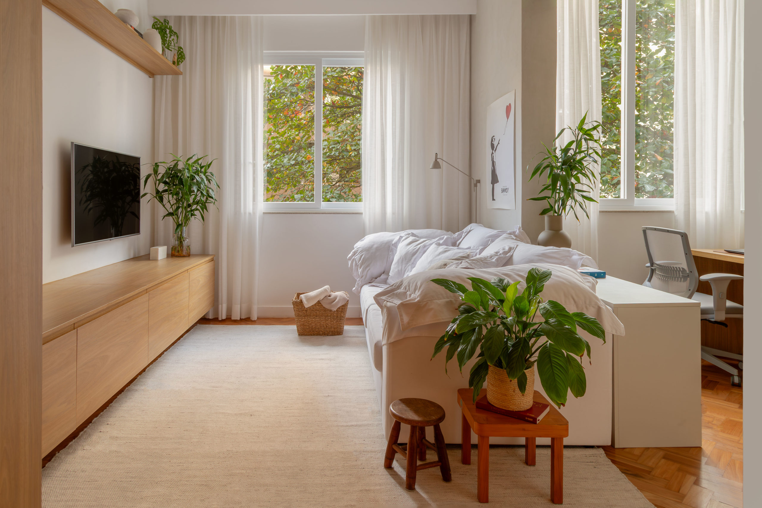 na foto sala de TV, janela com cortina branca e plantas