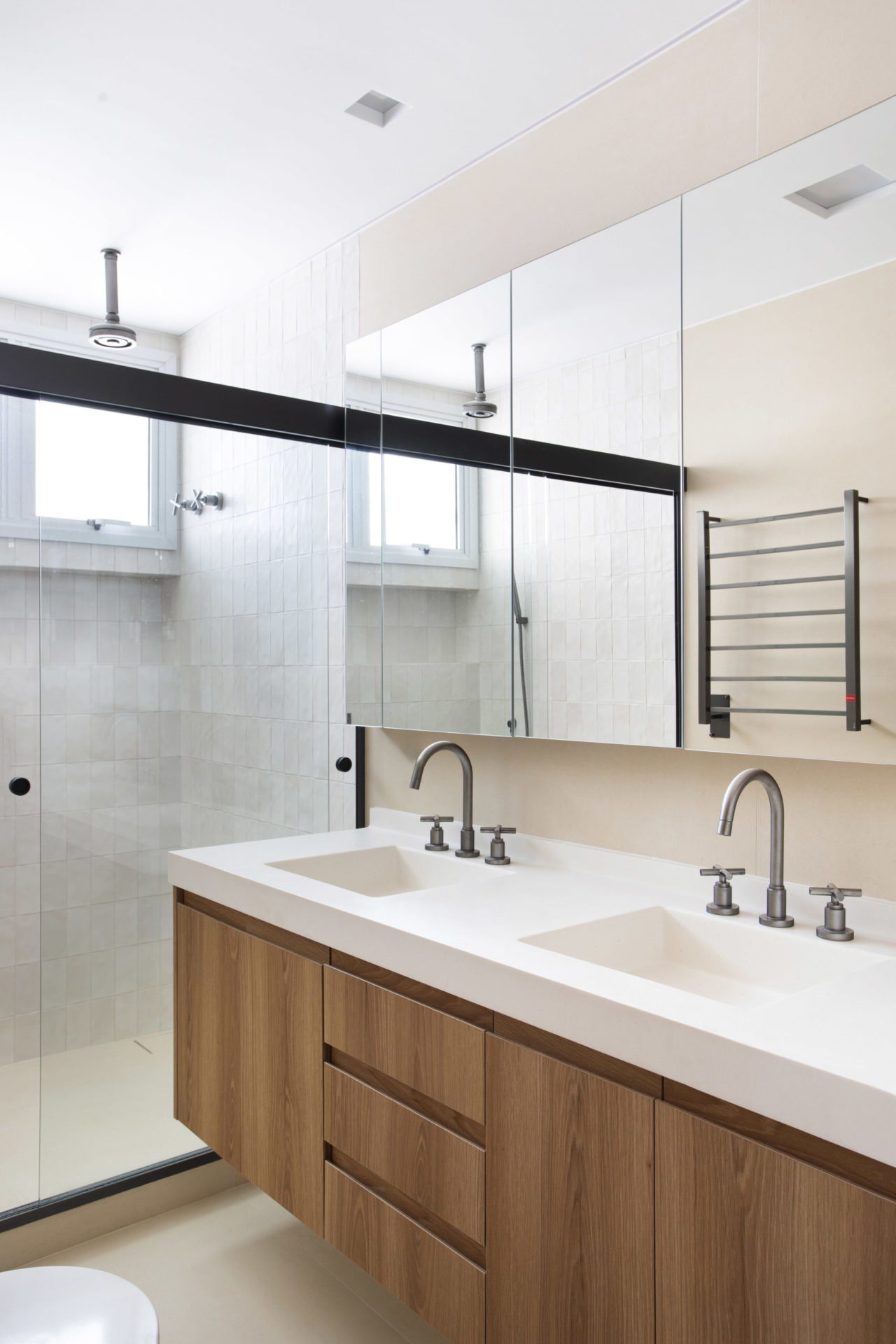 na foto banheiro com bancada branca e armário de madeira