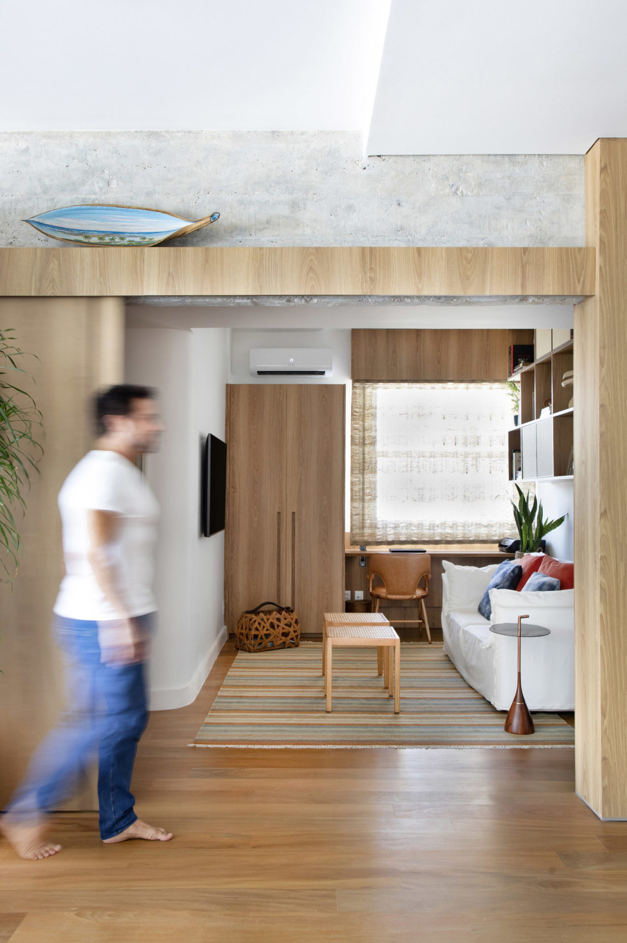 na foto espaço com piso em madeira, portas em madeira e um homem passando