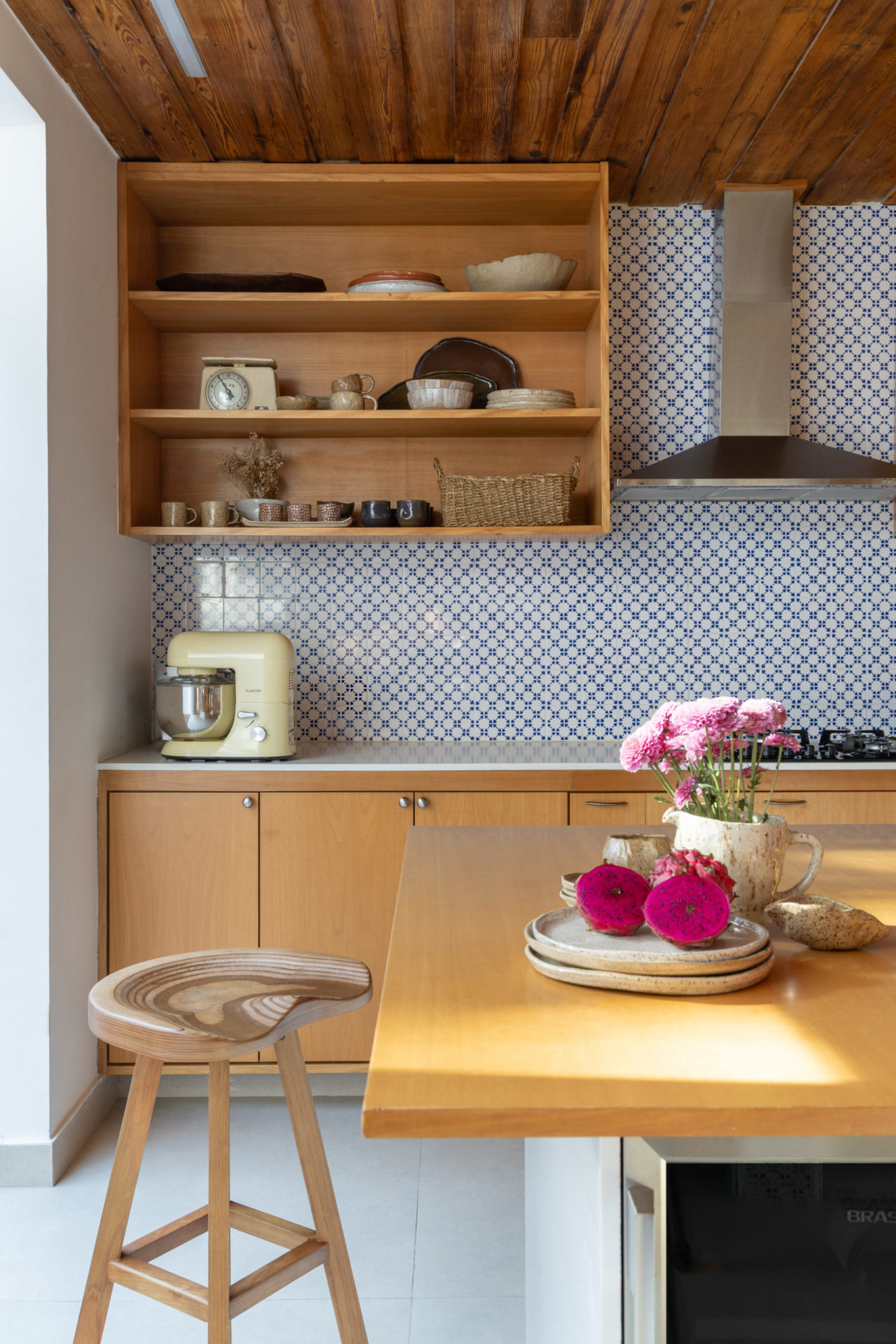 na foto cozinha em madeira e flores na bancada