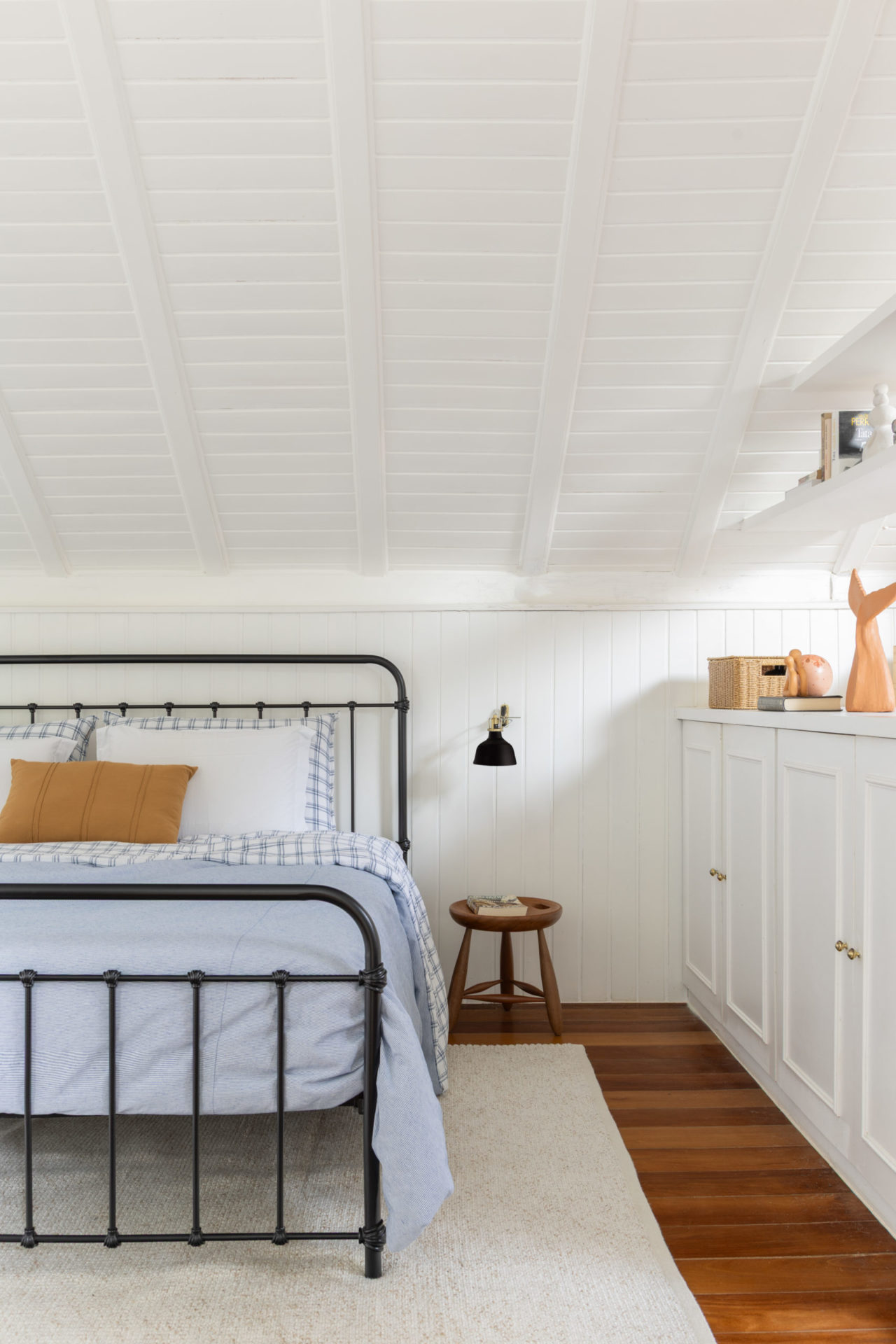 na foto quarto com cama e o banquinho Mocho, de Sergio Rodrigues