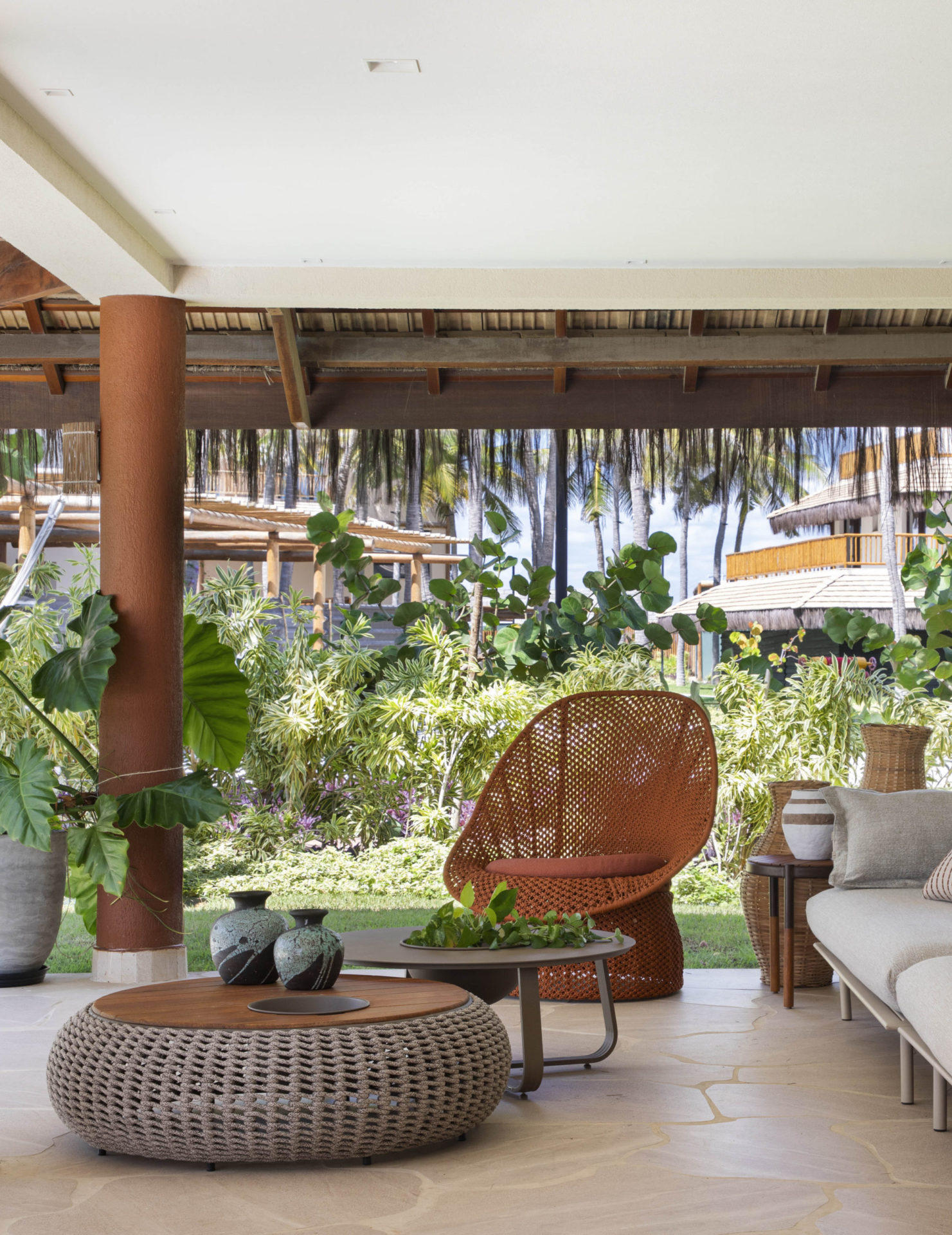 na foto varanda com sofá, mesinha e cadeira de frete para o jardim