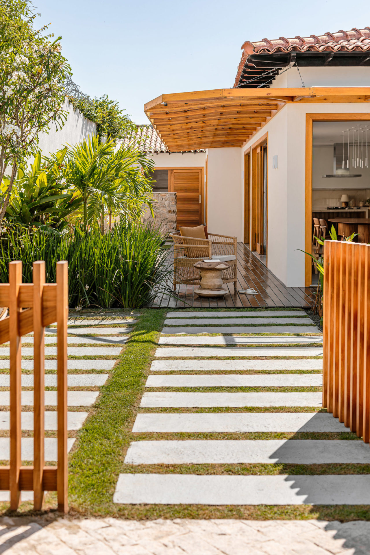 Na foto a entrada de uma casa térrea na cores branca e amarela. cerca de madeira