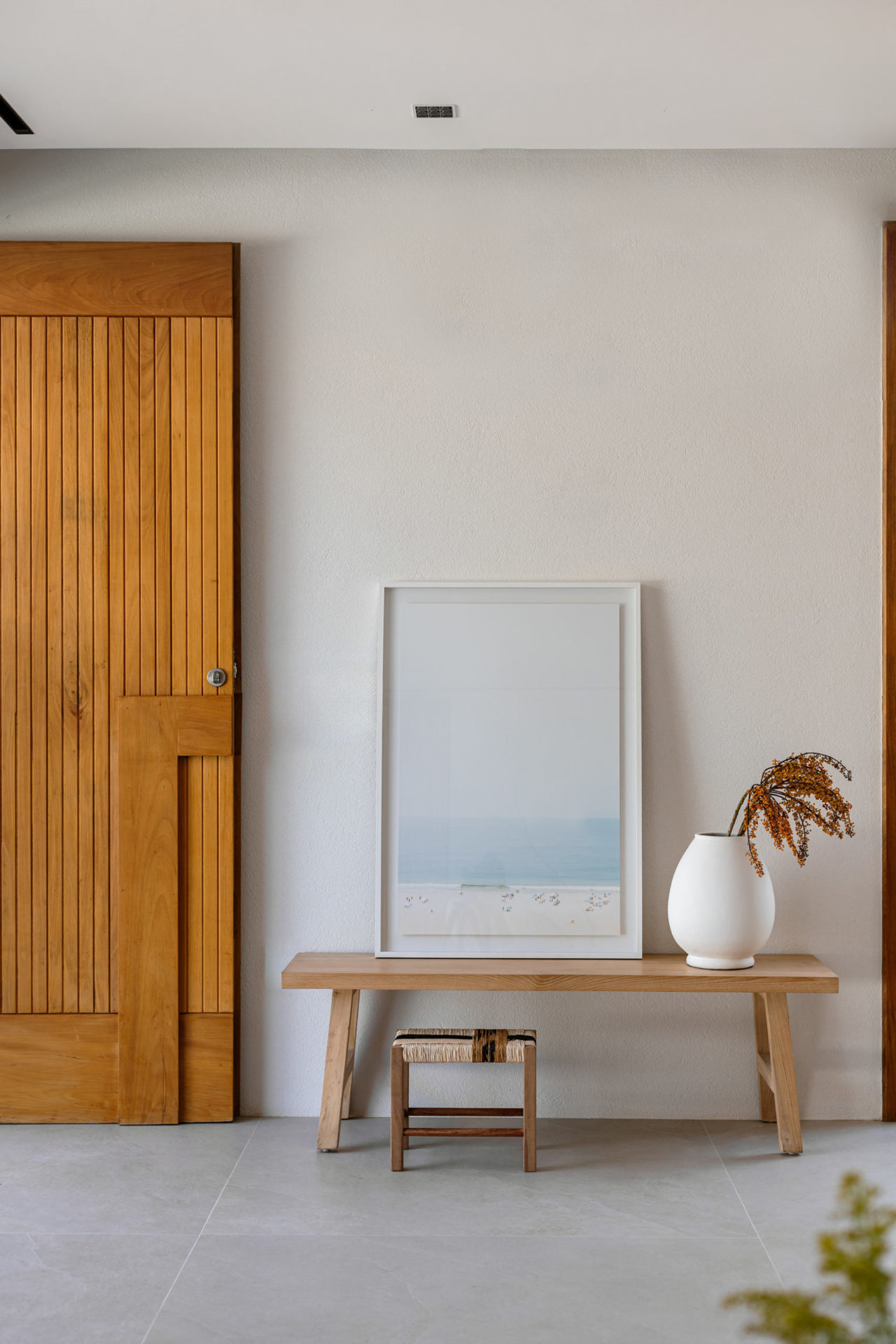 na foto mesa de canto com quadro e vaso com flores