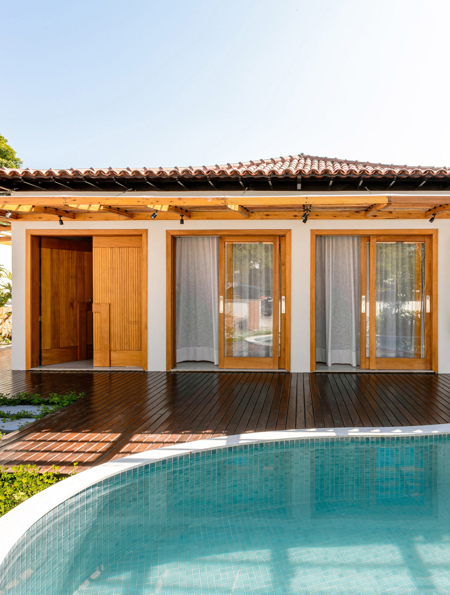 na foto casa térrea com tons claros, texturas sutis e amplos vãos envidraçados