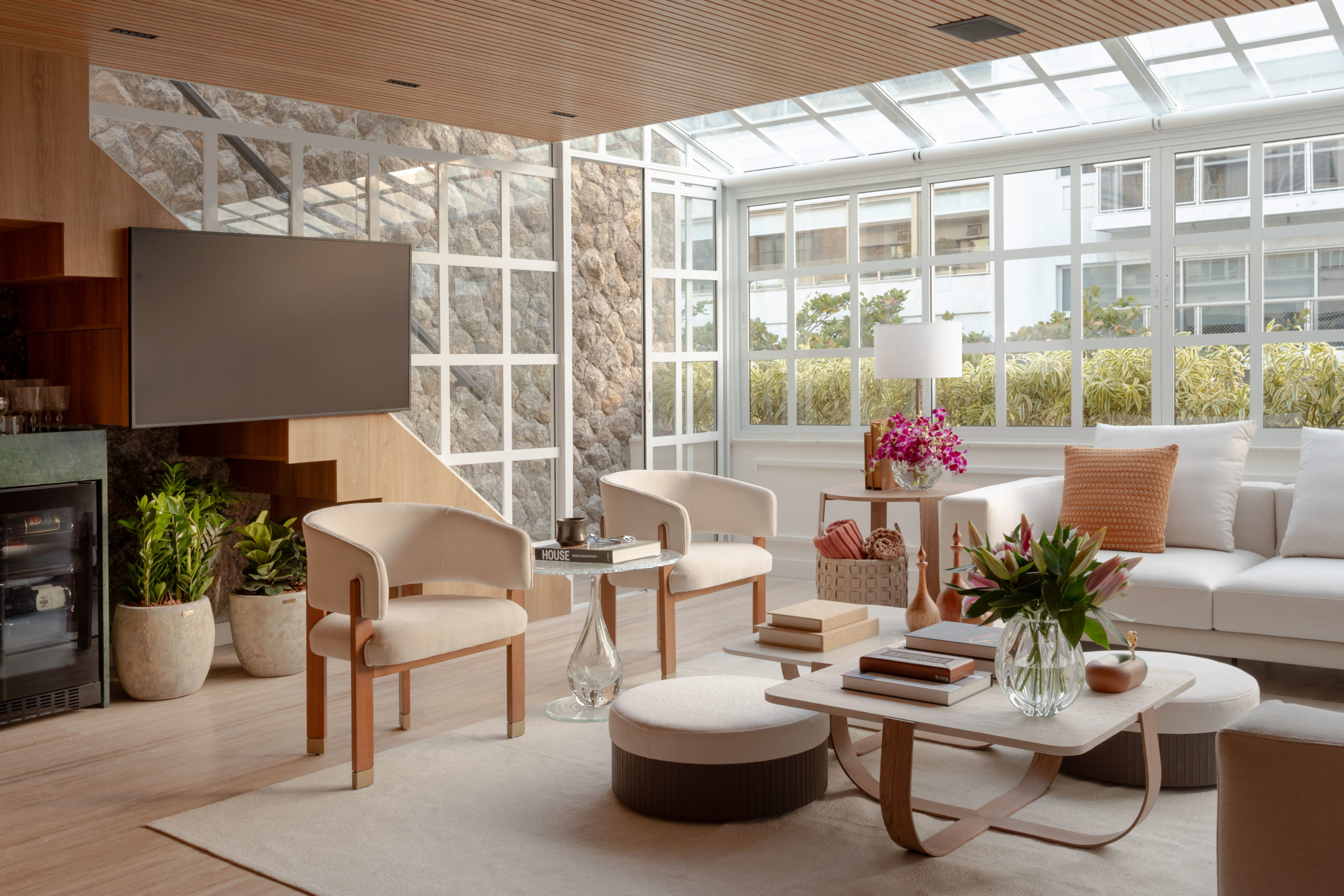 na foto sala com grande janela, mesa de centro, sofá branco, das poltronas brancas e escada