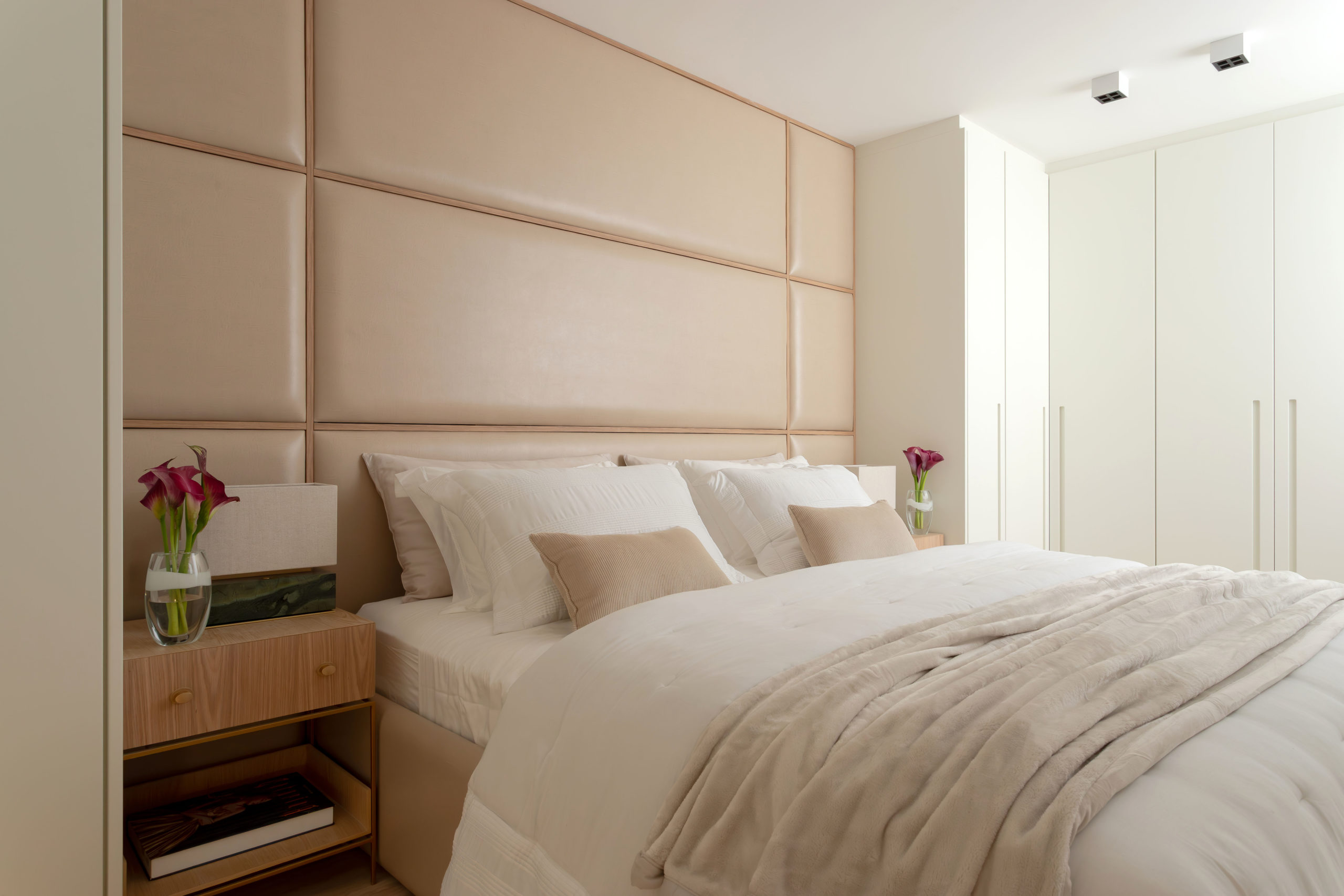 na foto quarto com cama de casal, mesa de cabeceira em tons claros