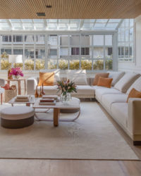 na foto sala ampla com mesa de centro, sofá, janelão e muita luminosidade