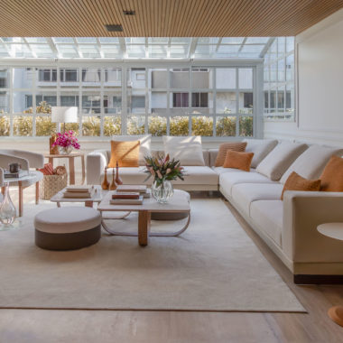 na foto sala ampla com mesa de centro, sofá, janelão e muita luminosidade