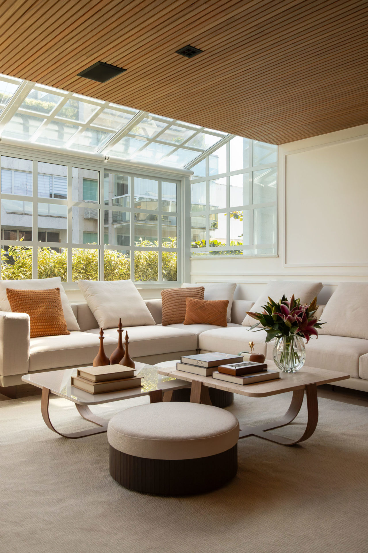 na foto sala com grande janela, sofá branco, mesa de centro com arranjo de flores