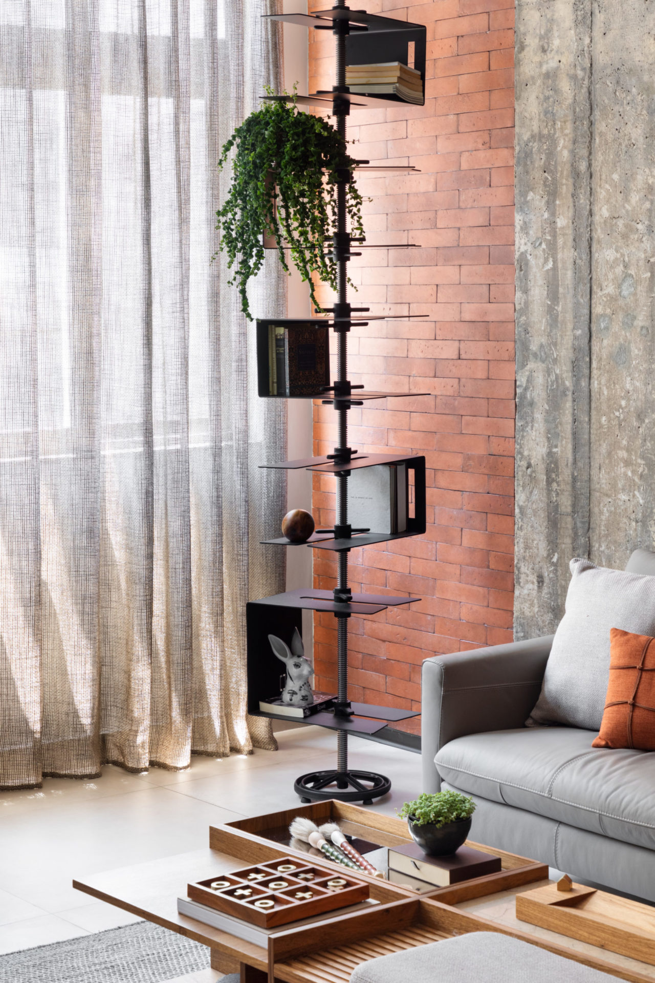 na foto sala com estante escultural e sofá cinza