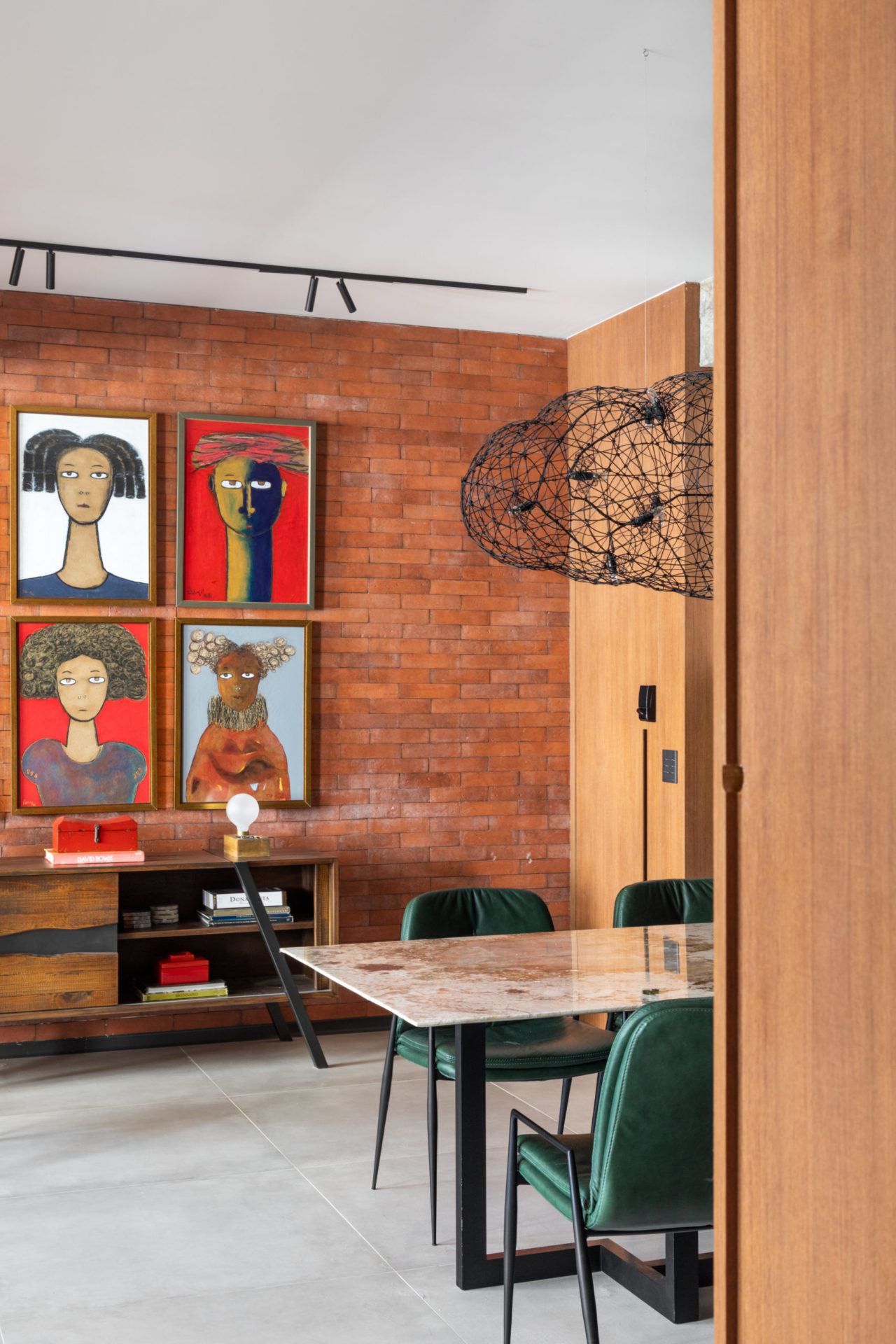 na foto loft com paredes de tijolos, quadros na parede e uma mesa de jantar