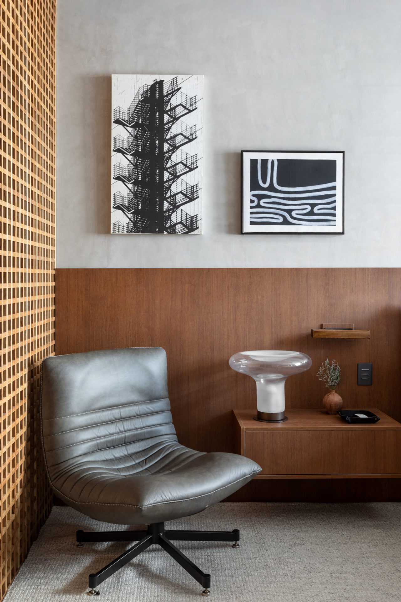 na foto canto de cômodo com poltrona preta de couro e dois quadros em preto e branco na parede