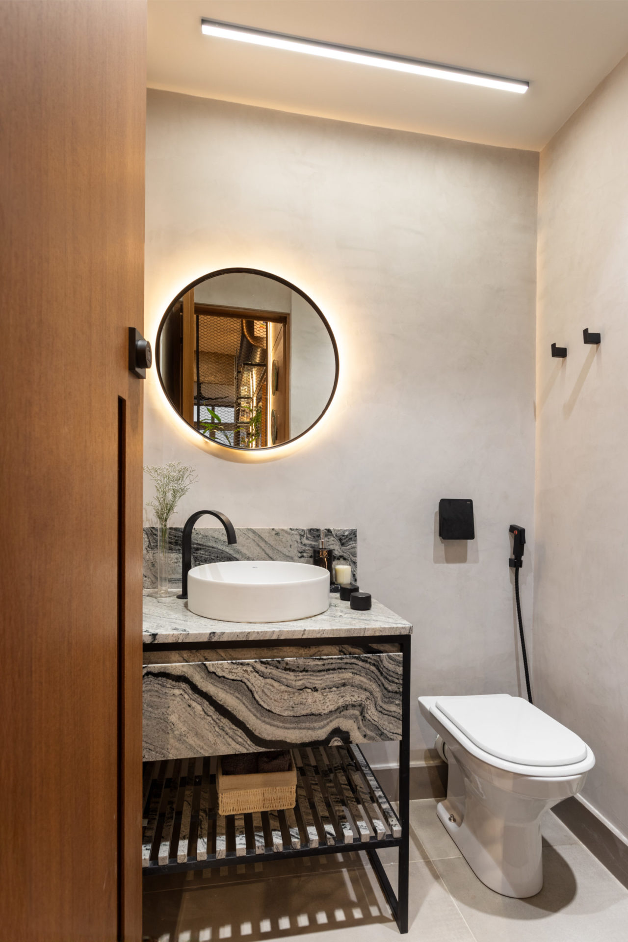 na foto lavabo com espelho redondo e iluminado