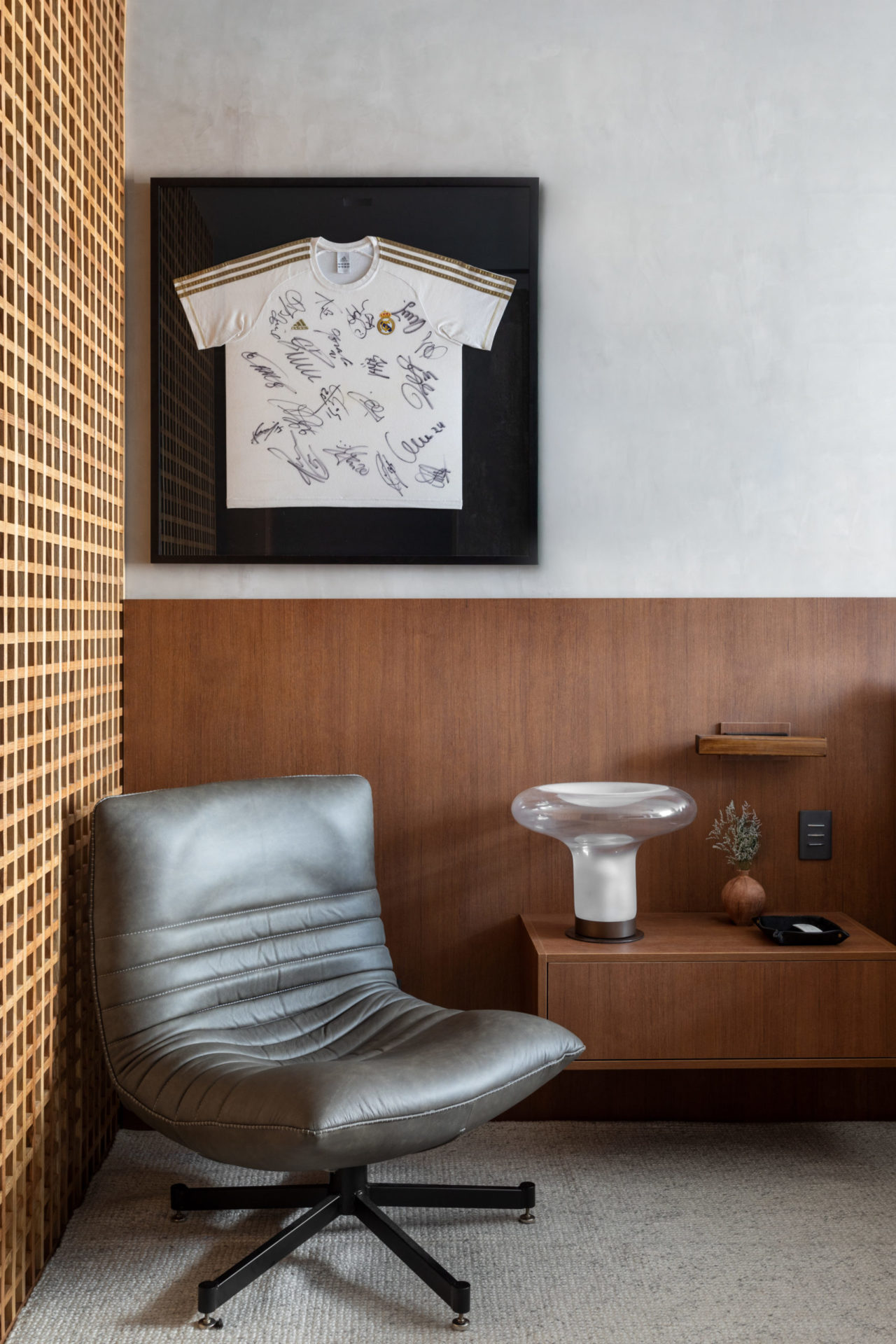 na foto uma poltrona, uma mesinha de cabeceira e um quadro com uma camisa autogragada