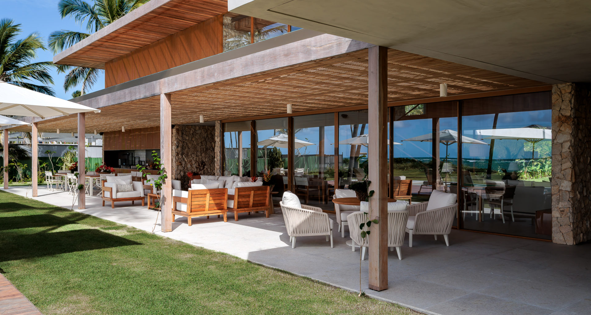 na foto varanda de casa de praia com amplo jardim e árvores