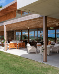 na foto varanda de casa de praia com amplo jardim e árvores