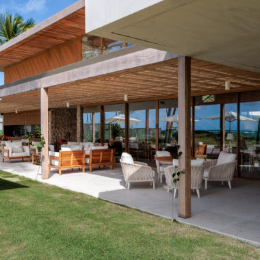 na foto varanda de casa de praia com amplo jardim e árvores