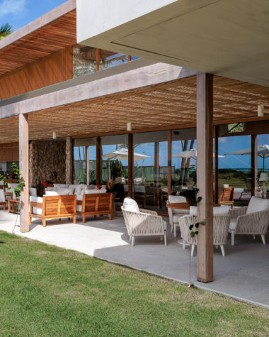 na foto varanda de casa de praia com amplo jardim e árvores