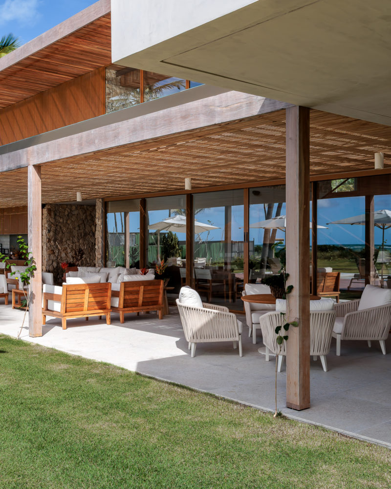 na foto varanda de casa de praia com amplo jardim e árvores