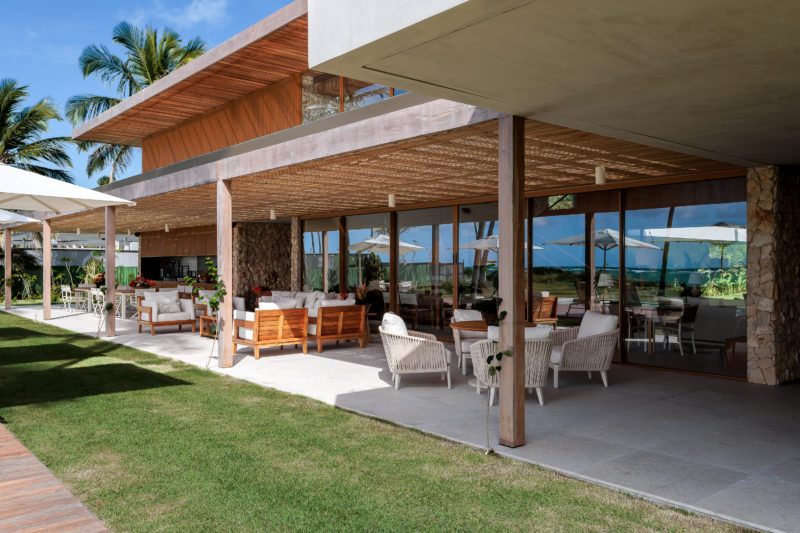 na foto varanda de casa de praia com amplo jardim e árvores