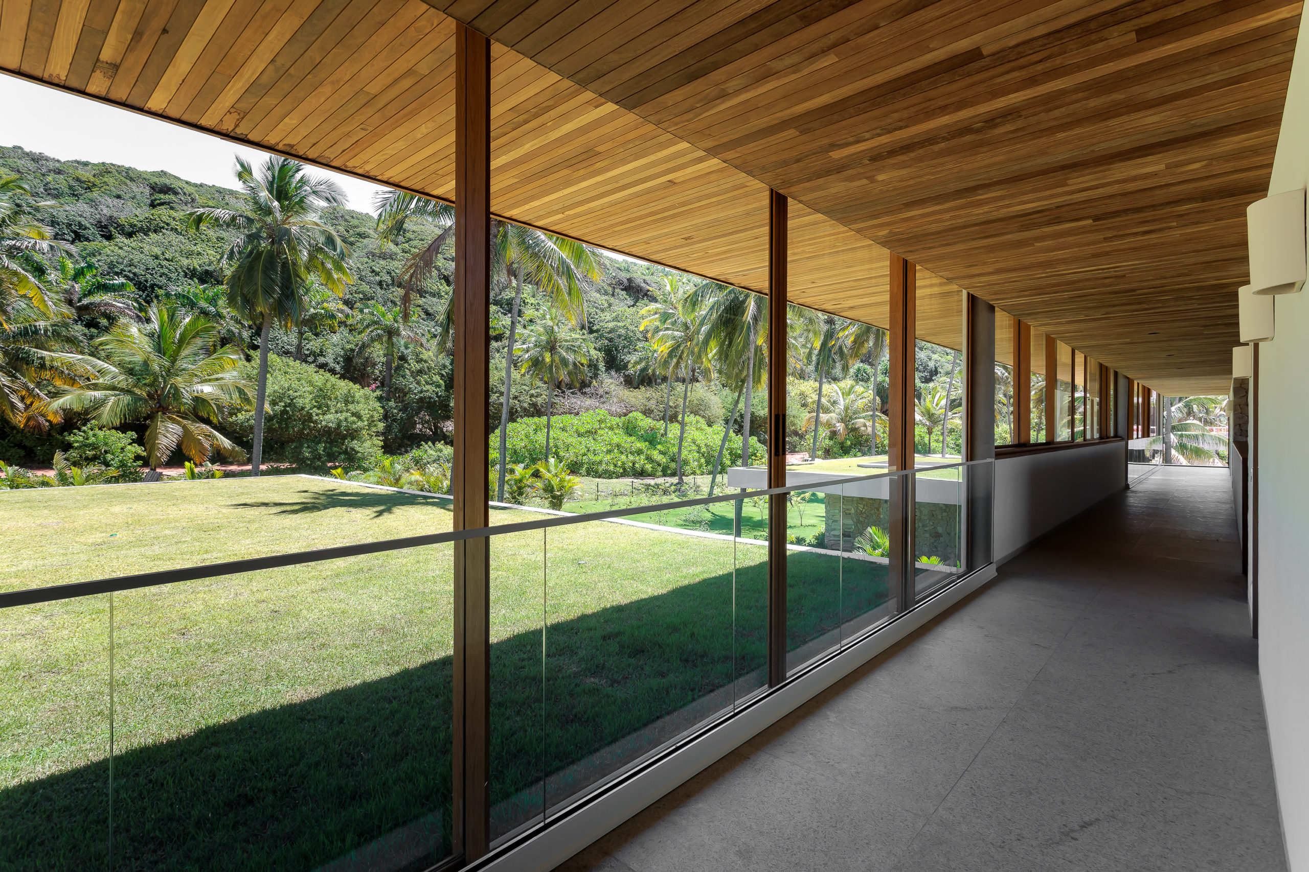 na foto casa de praia com lajes de concreto revestidas de madeira e grande jardim e 