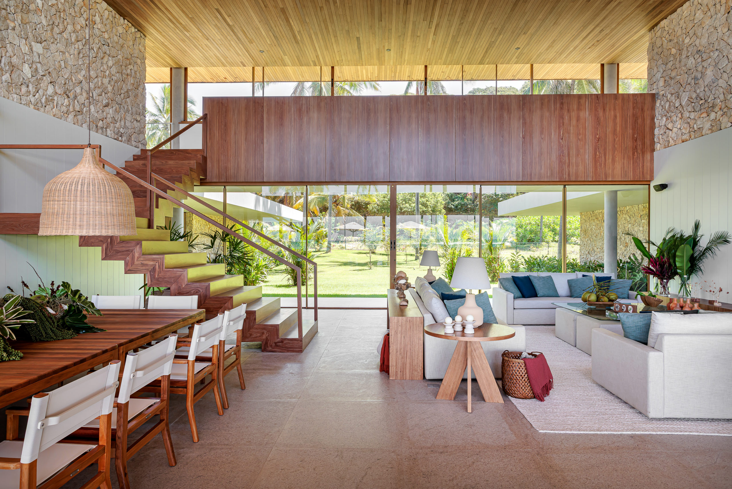 na foto uma ampla sala com vista para jardim e segundo pavimento