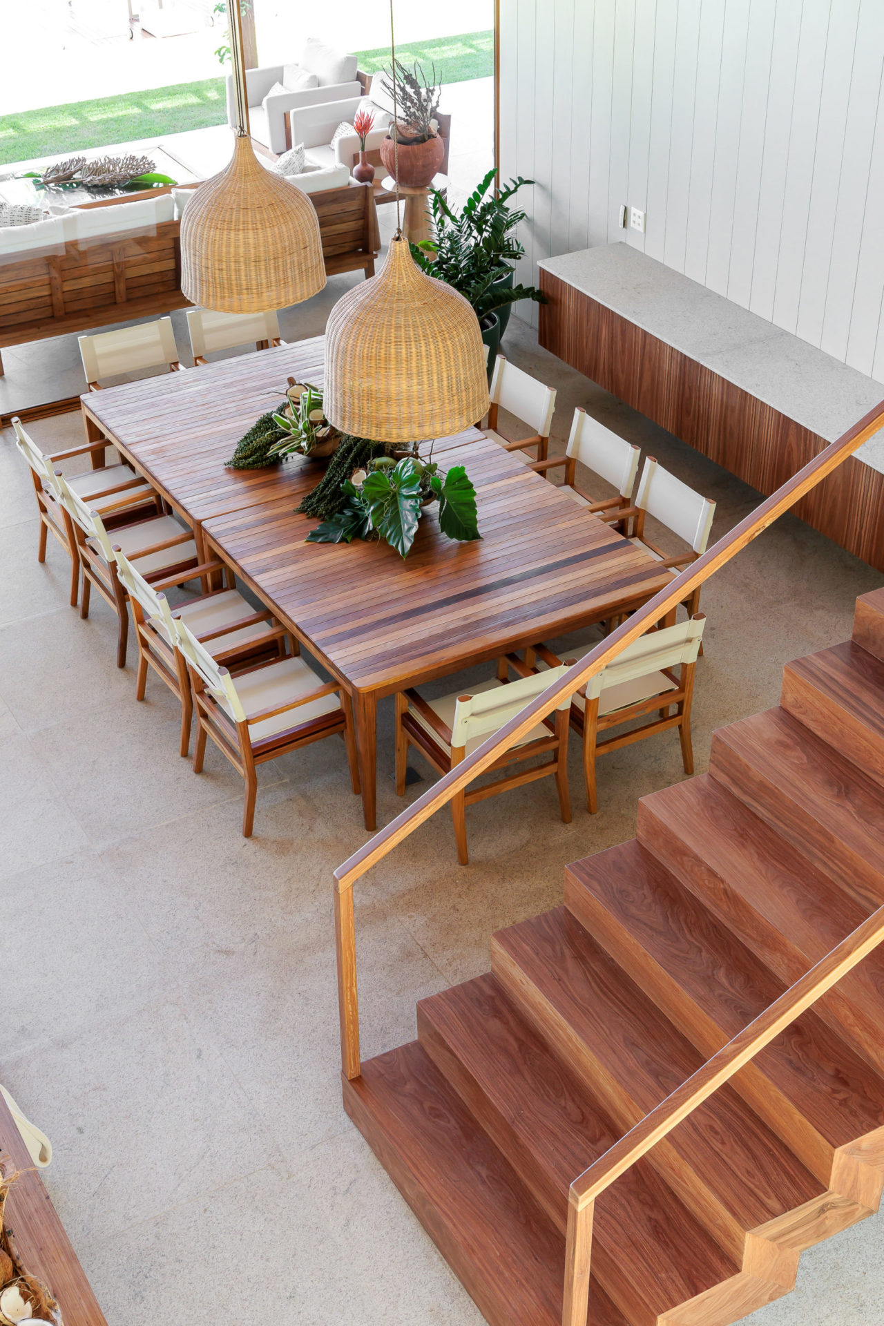 na foto sala de jantar com mesa de madeira e escada