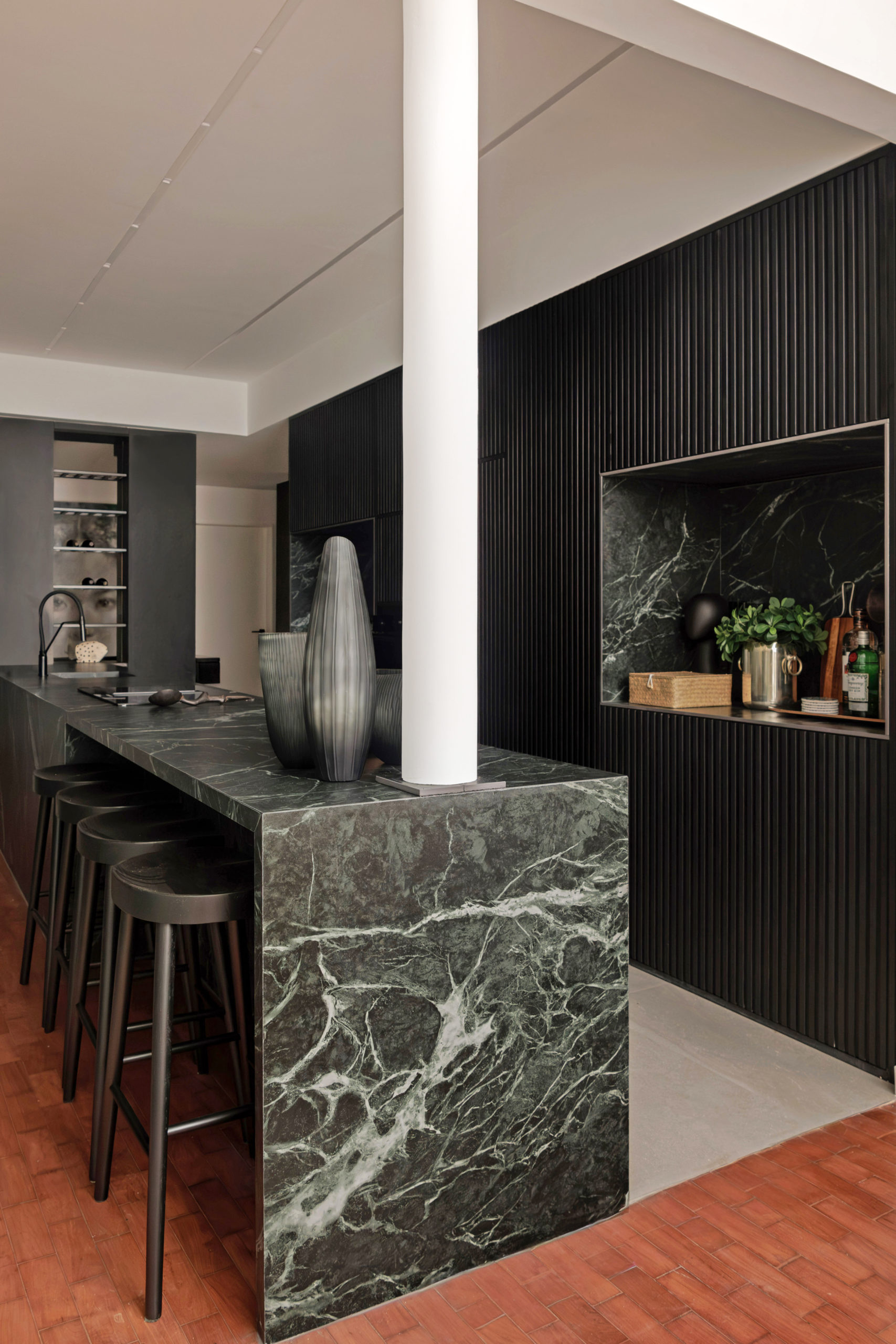 Cozinha integrada com uma enorme bancada em pedra verde