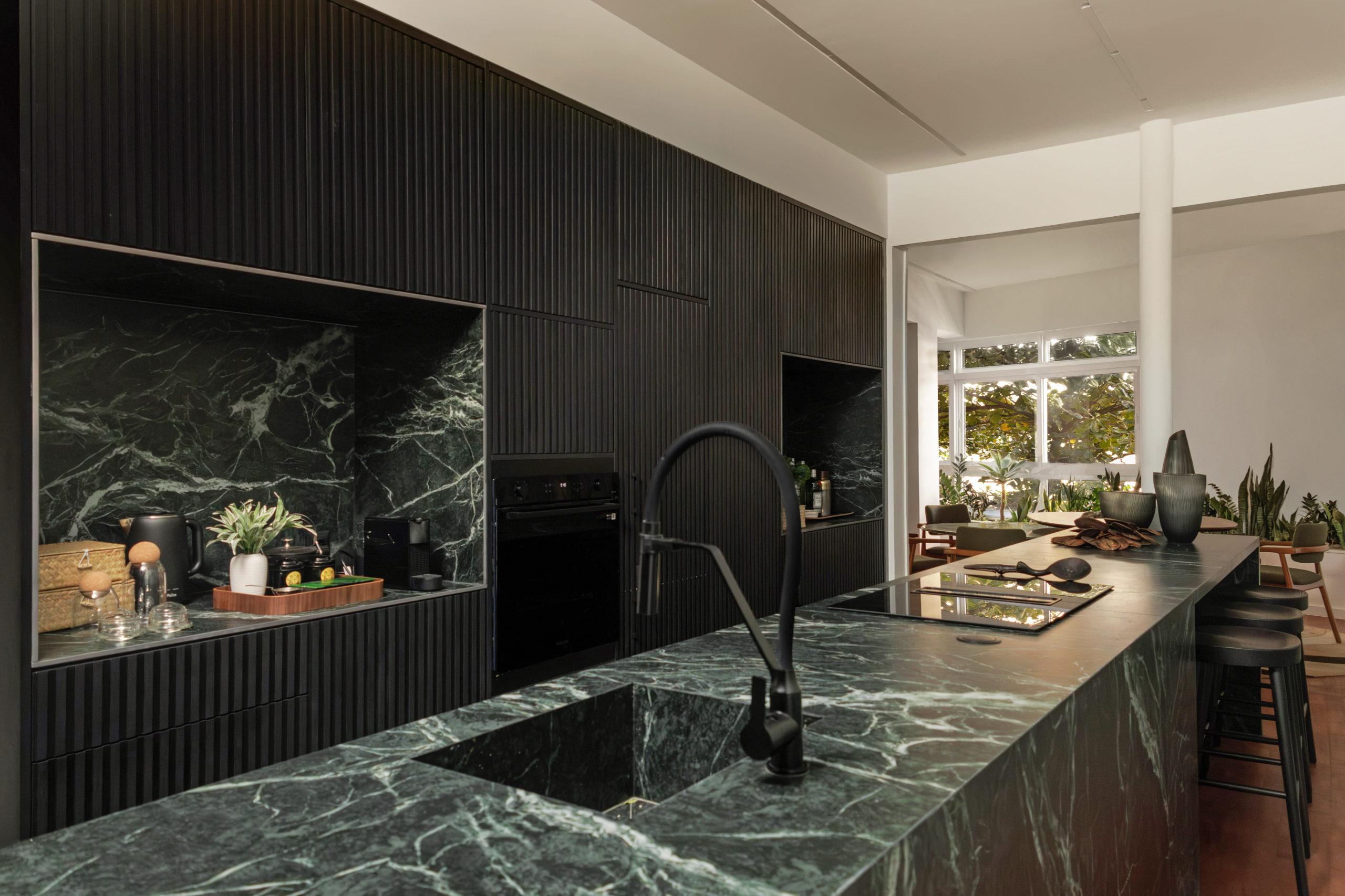 na foto cozinha em mármore escuro integrada à sala