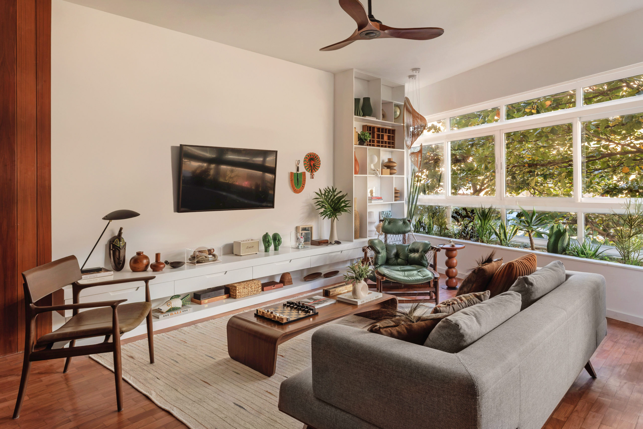 na foto sala de tv, estar e grande janela para rua arborizada