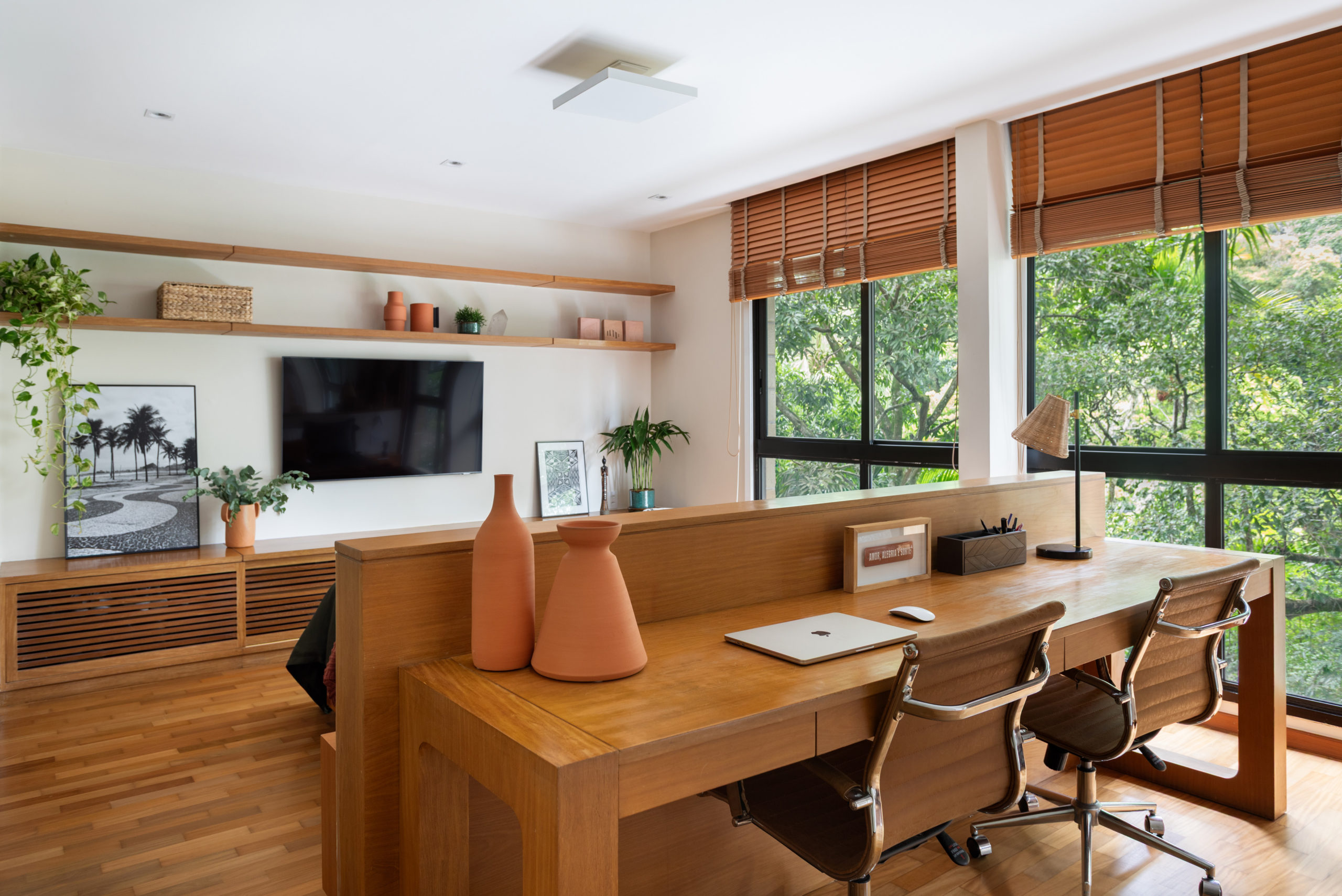 na foto sala com sofá e tv na parede e mesa de escritório