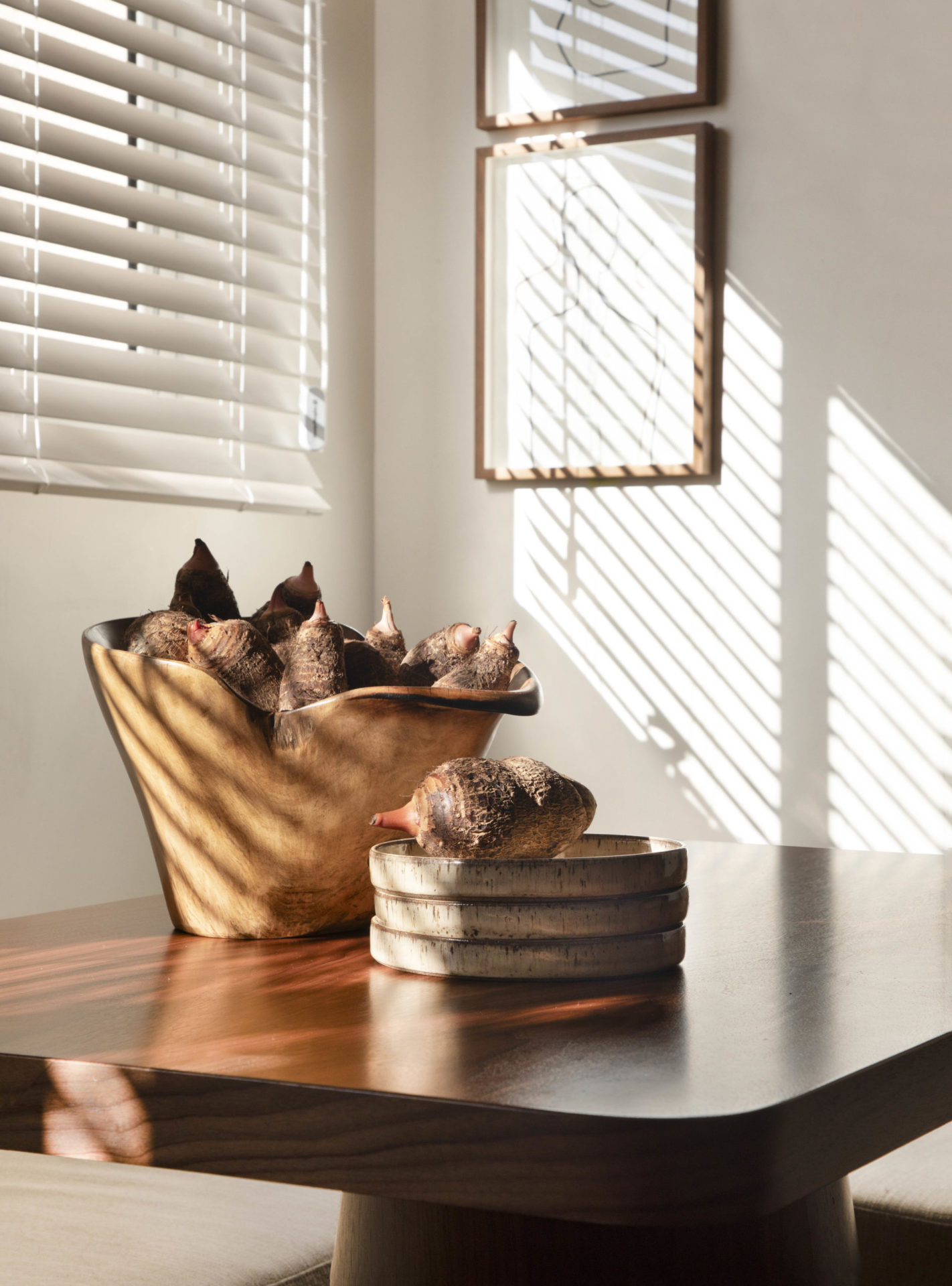 na foto mesa de madeira escura com arranjos sobre e um quadro na parede