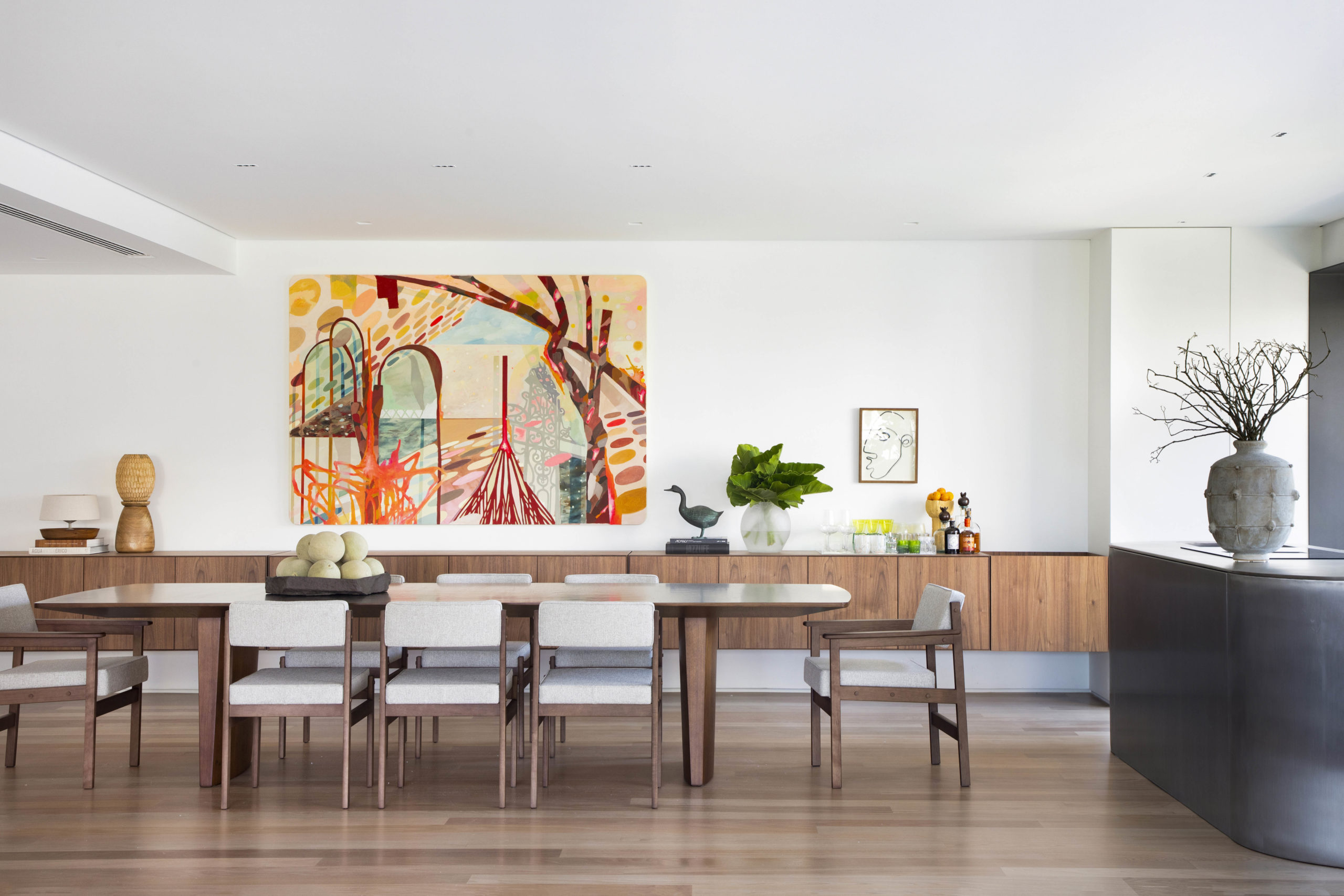na foto mesa de jantar em madeira, grande quadro colorido na parede