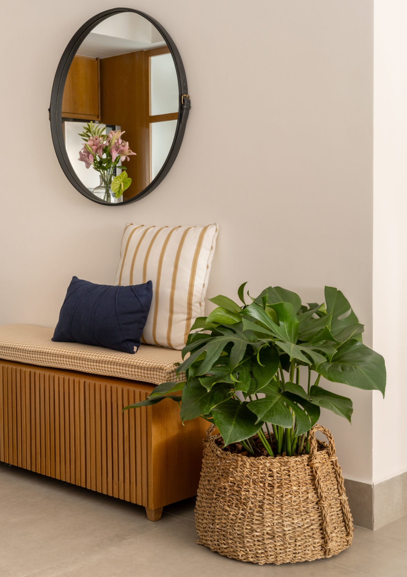 na foto banco de madeira, vaso de planta e espelho redondo