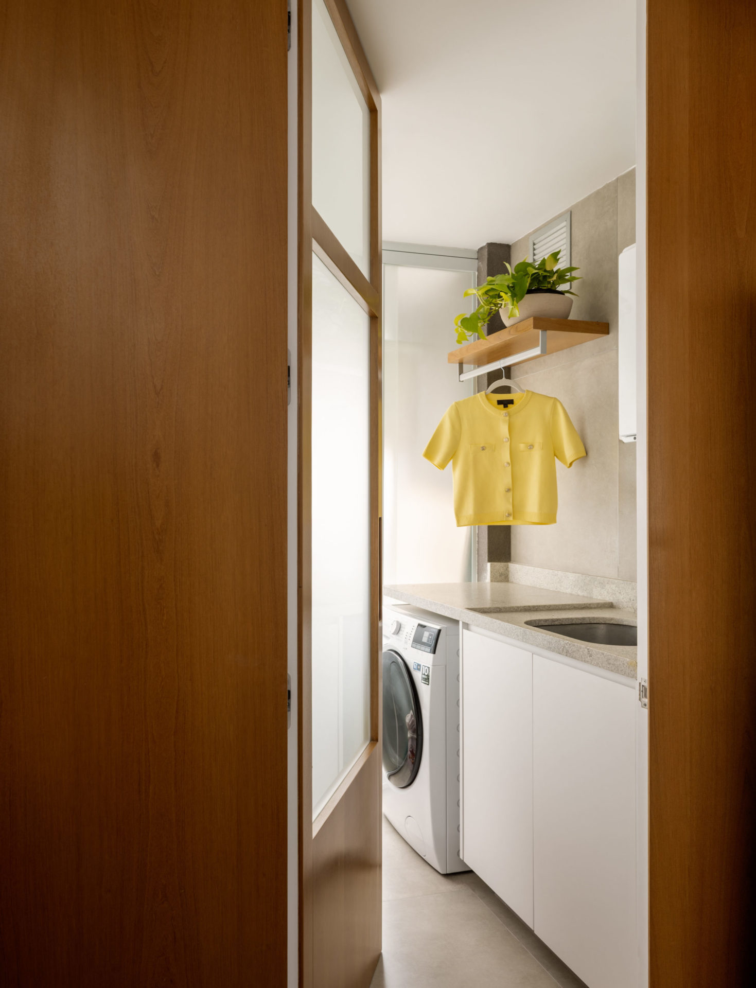 na foto área de serviço com máquina de lavar e roupas penduradas