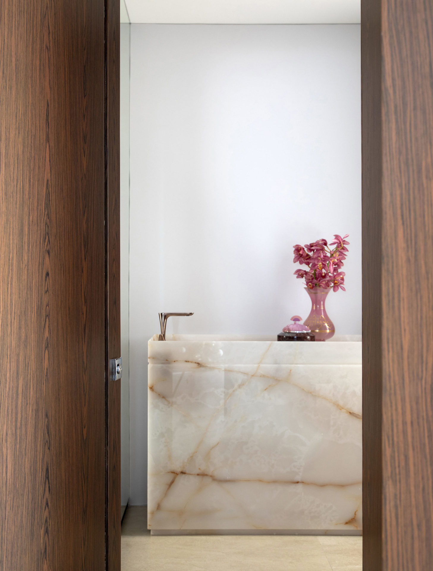 na foto lavabo marmorizado e flores na bancada