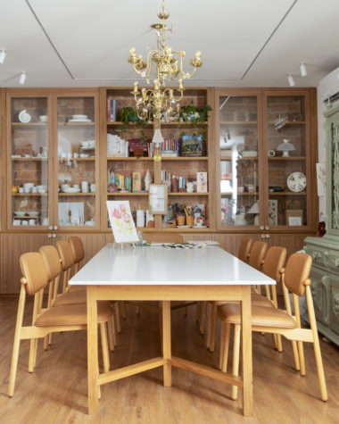 na foto mesa com seis cadeiras, duas estantes de madeira, lustre de ferro e espelho com moldura vermelha