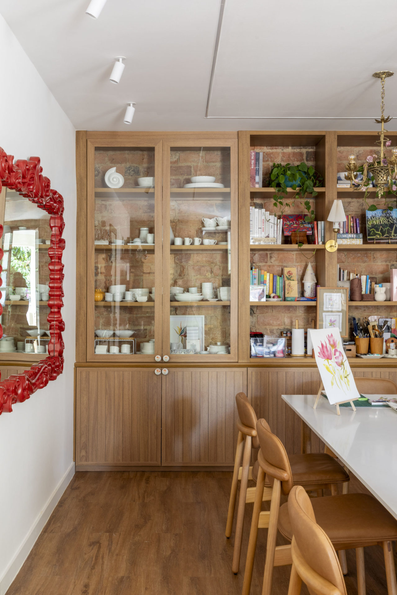 na foto estante de madeira, quadro com moldura vermelha e mesa 