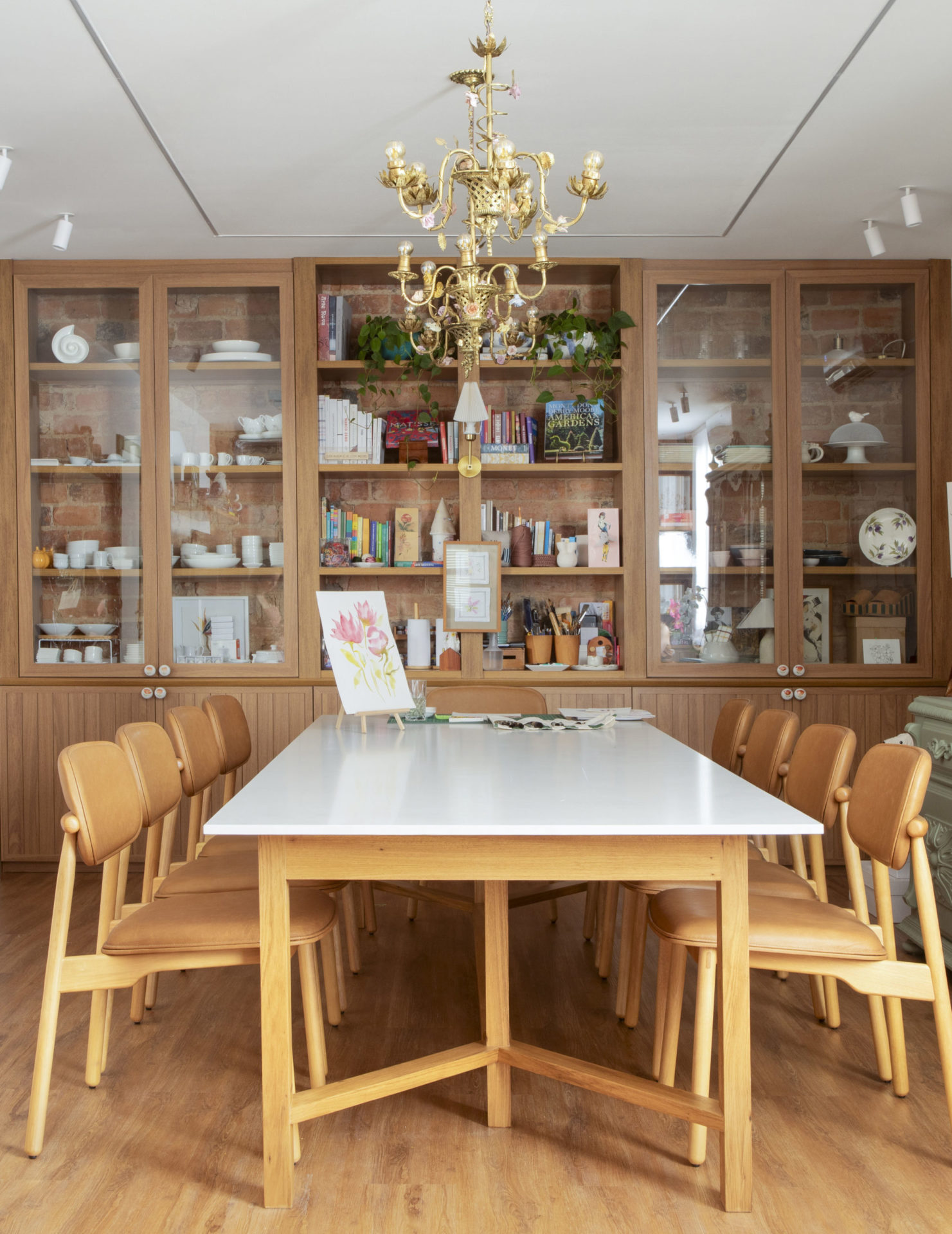 na foto mesa de atelier, estante de madeira e lustre