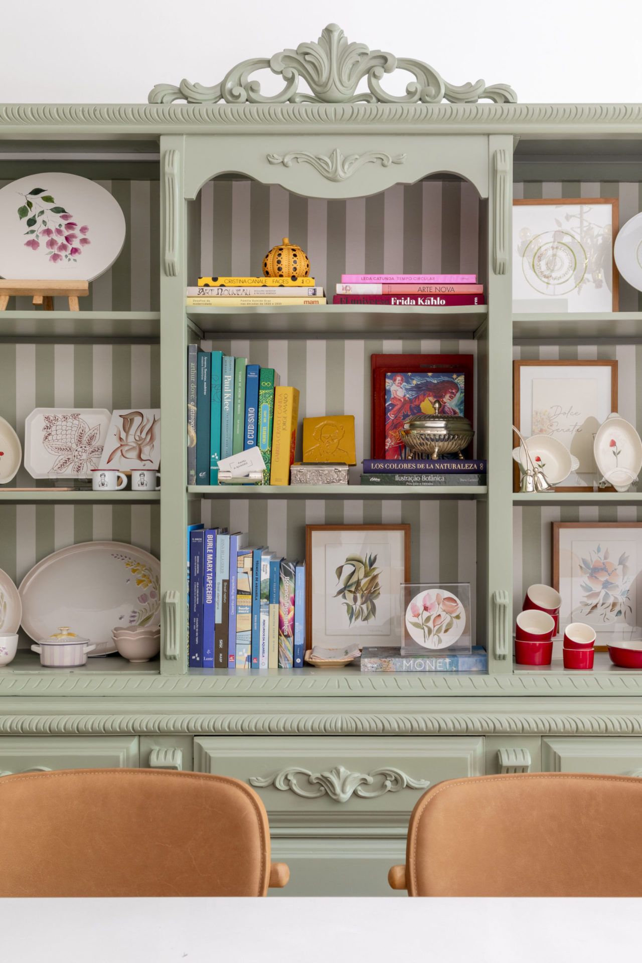 na foto estante verde com quadros e porcelanas