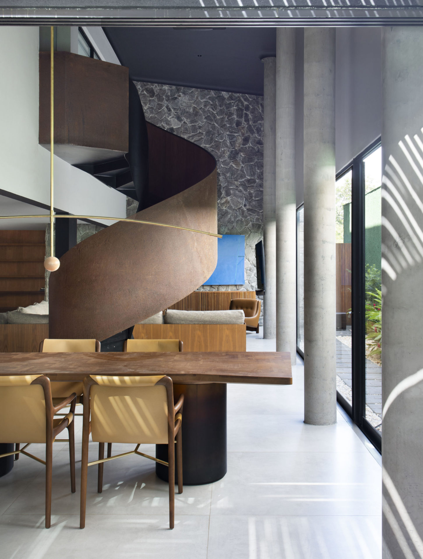 na foto parte interna da casa com escada helicoidal e móveis em madeira