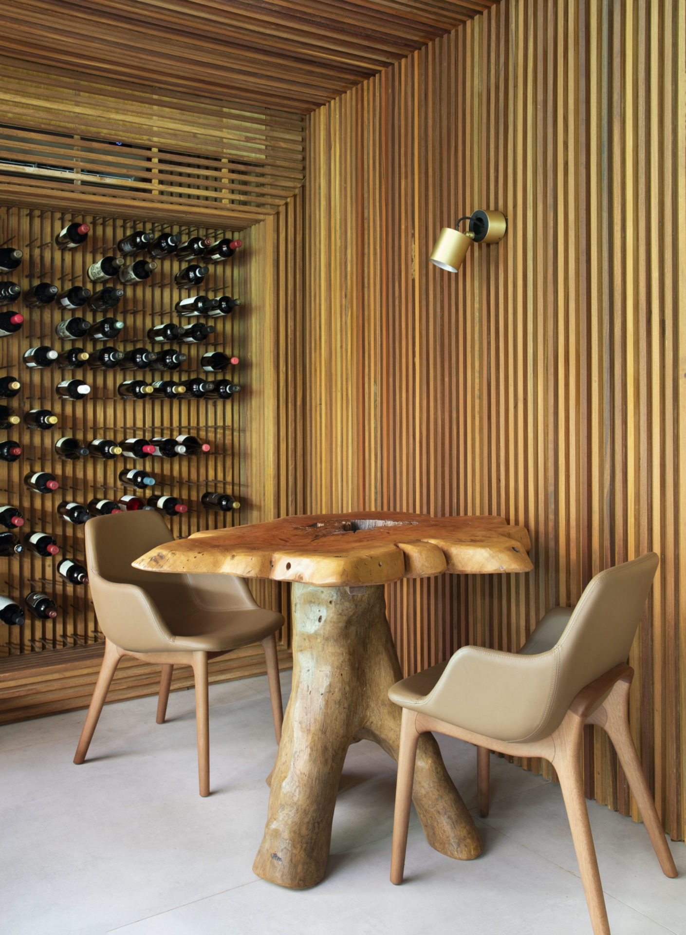 na foto adega vertical, localizada na parede, e uma mesa com duas cadeiras