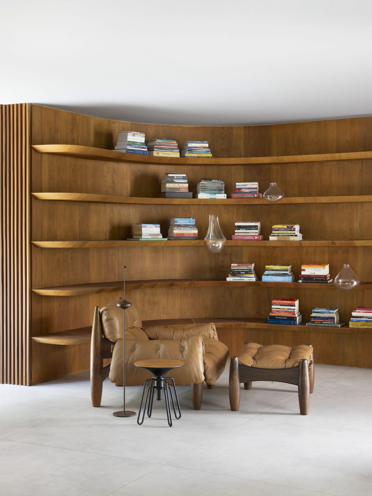 na foto poltrona de couro e estante com livros