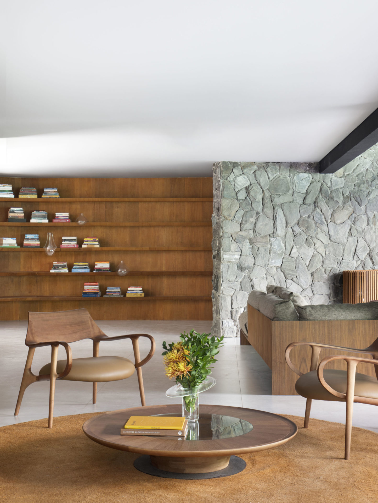 na foto sala com estante com livros e poltronas de couro