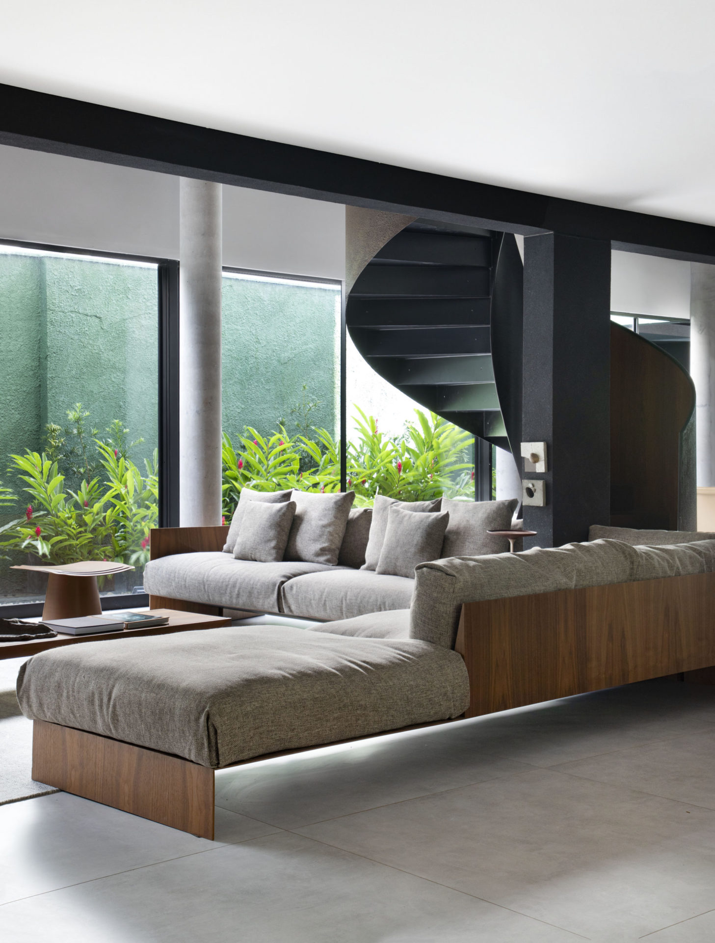 na foto sala com dois andares e escada caracol